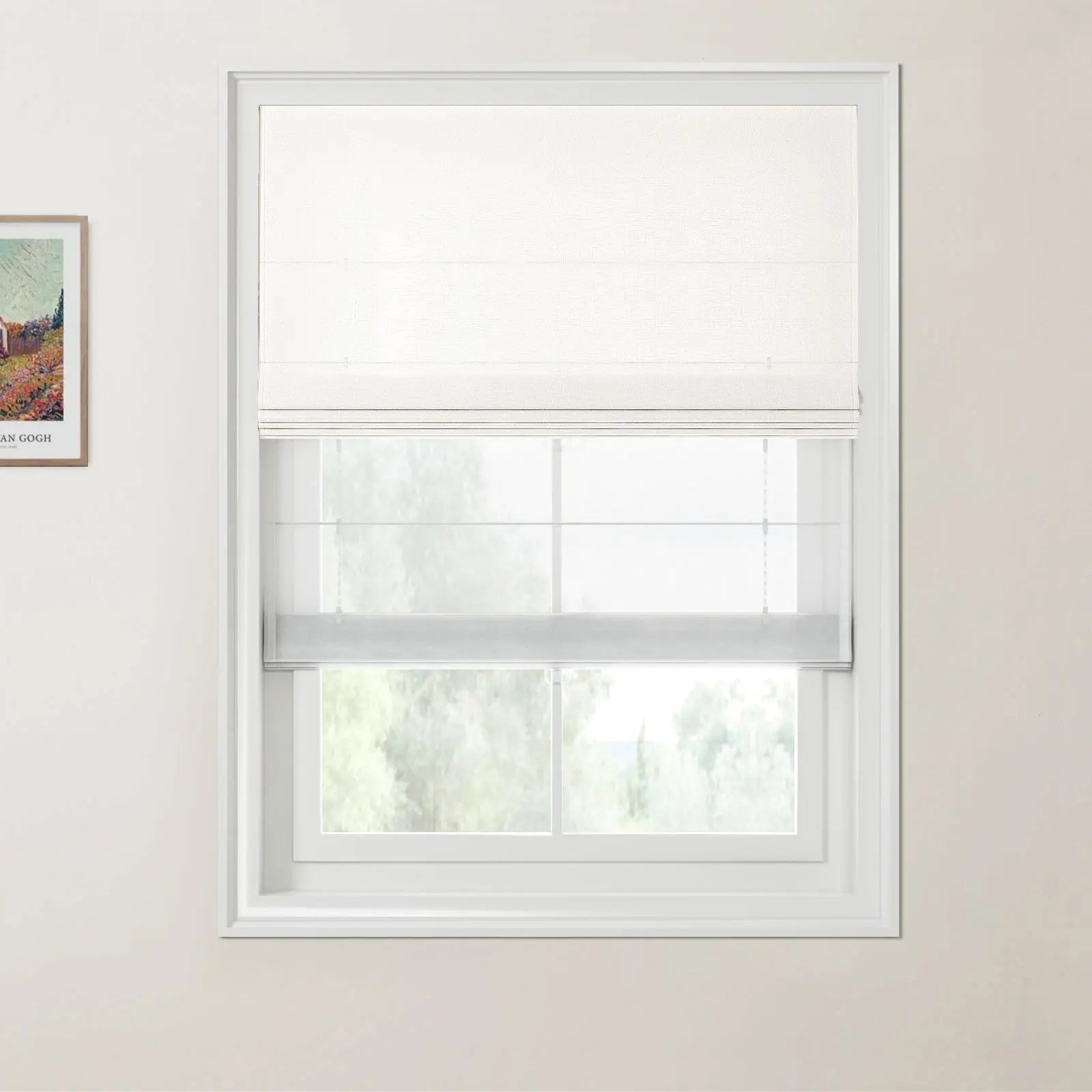 Photograph of a white window with dual white cellular and Roman blinds, offering a blurred green outdoor view, next to a partially visible framed Van Gogh print on a light wall