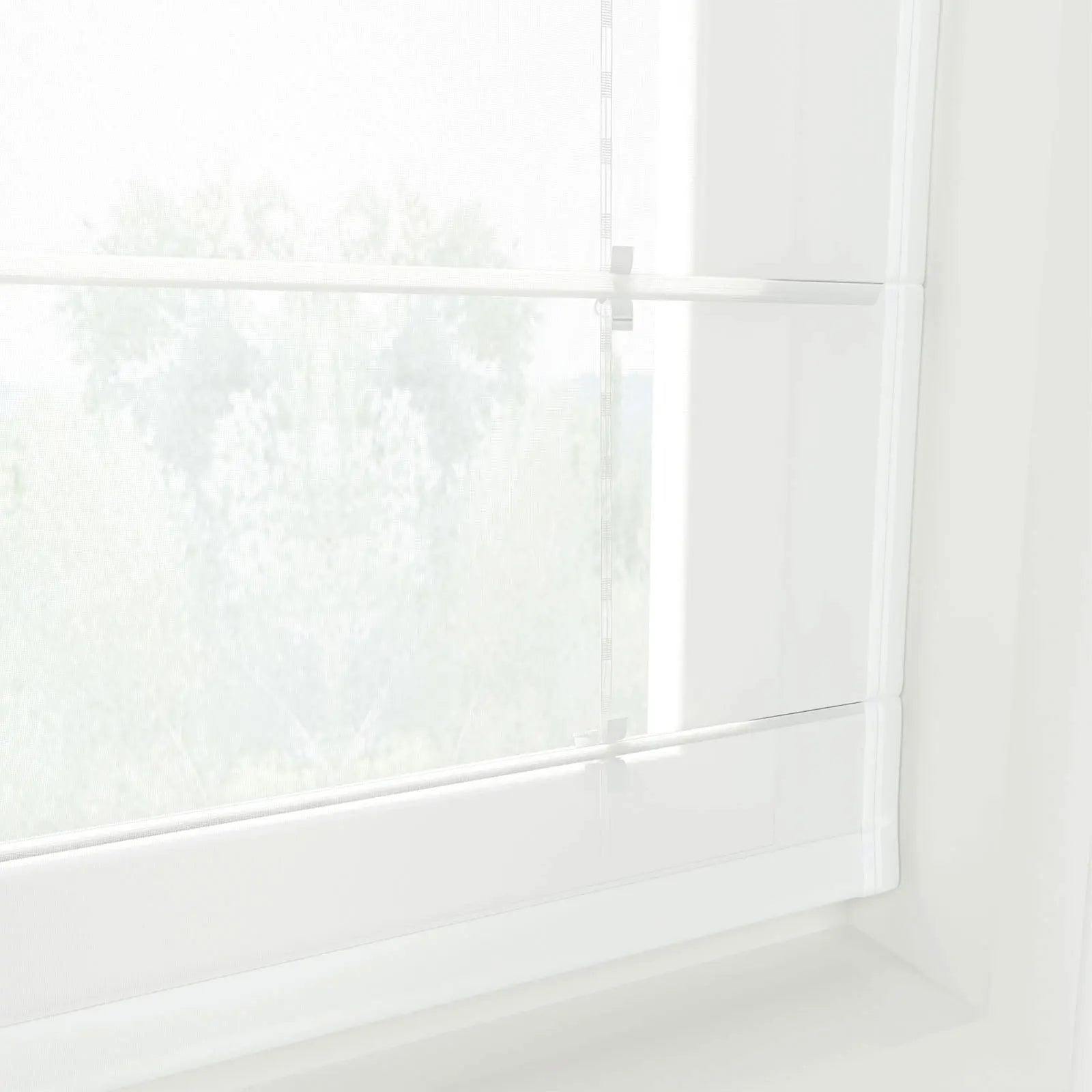 Photograph of a window with white sheer Roman blinds displaying blurred green foliage outdoors, featuring subtle vertical striped cords and bright diffused natural light creating a minimalist ambiance