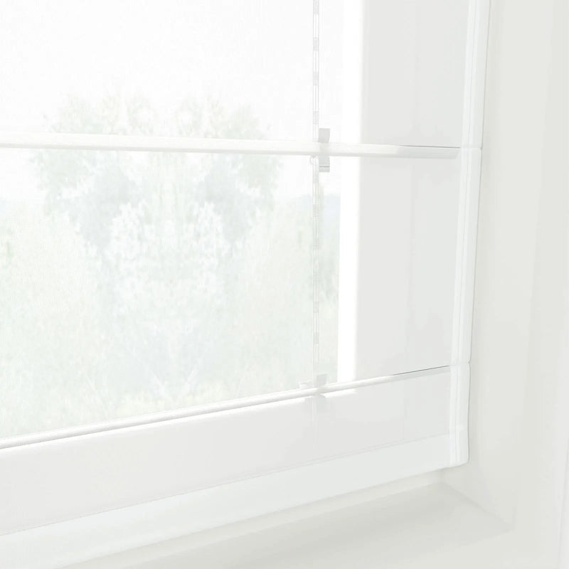 Photograph of a window with white sheer Roman blinds displaying blurred green foliage outdoors, featuring subtle vertical striped cords and bright diffused natural light creating a minimalist ambiance
