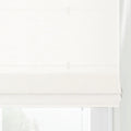 White Roman blind with a subtle grid pattern linen-like texture, partially lowered in a window with distinct horizontal folds