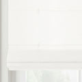 A white textured roman blind is neatly folded in layers, partially obscuring a window with soft diffused light behind it