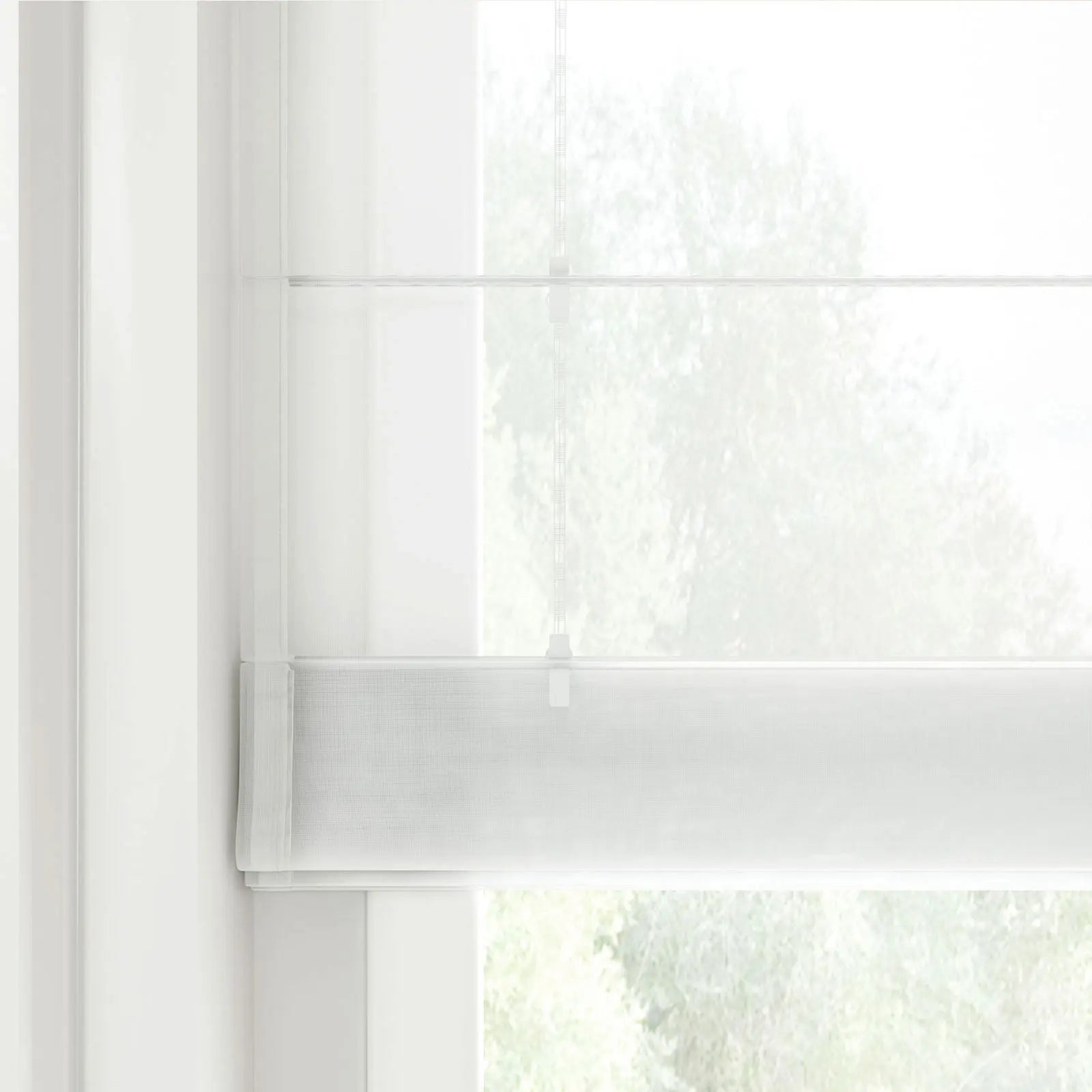Modern white sheer Roman blind with a subtle grid texture covering a window, with a faint cord mechanism visible and blurred green foliage outside
