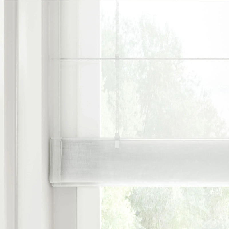 Modern white sheer Roman blind with a subtle grid texture covering a window, with a faint cord mechanism visible and blurred green foliage outside