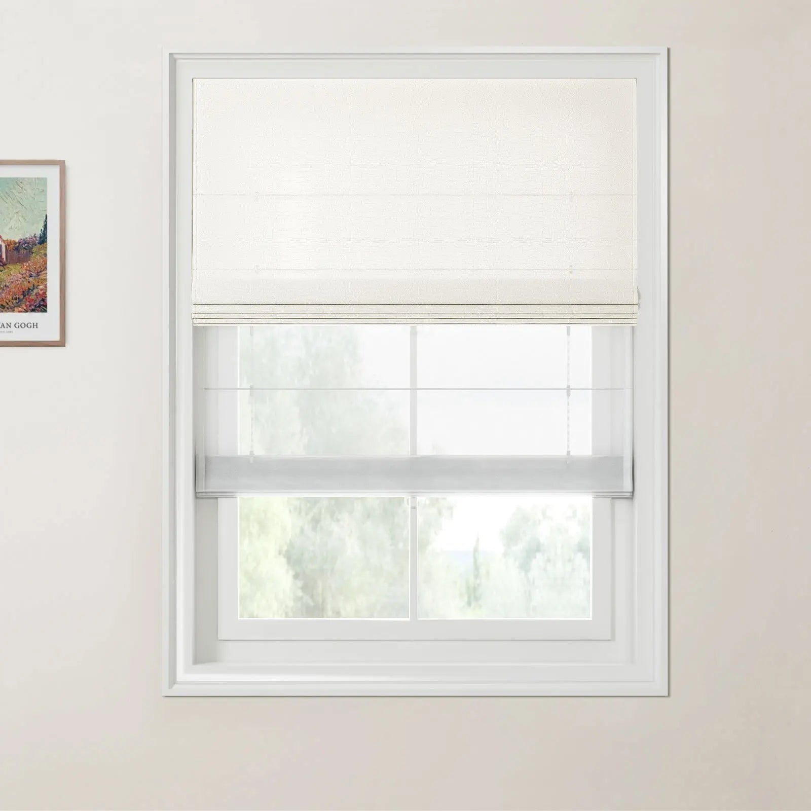 Photograph of a window featuring a cream textured opaque Roman blind above a sheer white one revealing soft green trees outside with white window trim and a framed Van Gogh landscape painting on the light beige wall
