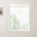 Photograph of an off-white room featuring a framed colorful landscape print by Van Gogh and a large white window with a cream textured Roman blind overlooking blurry light green trees