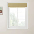 Photograph of a white six-pane window featuring a neatly folded textured golden yellow Roman blind, set against light beige walls with a partial Van Gogh print on the left, looking out to blurred green foliage