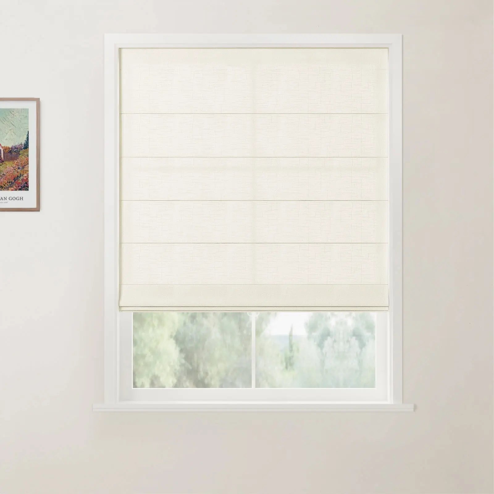 A photograph showcasing a window with a cream textured Roman blind featuring horizontal folds, set in a white frame, overlooking a blurred green landscape, with a framed Van Gogh print on the left wall