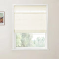Interior photo of a white-framed window with a cream textured roller blind partially lowered, revealing blurred green trees outside, and a framed Van Gogh landscape print on the adjacent white wall