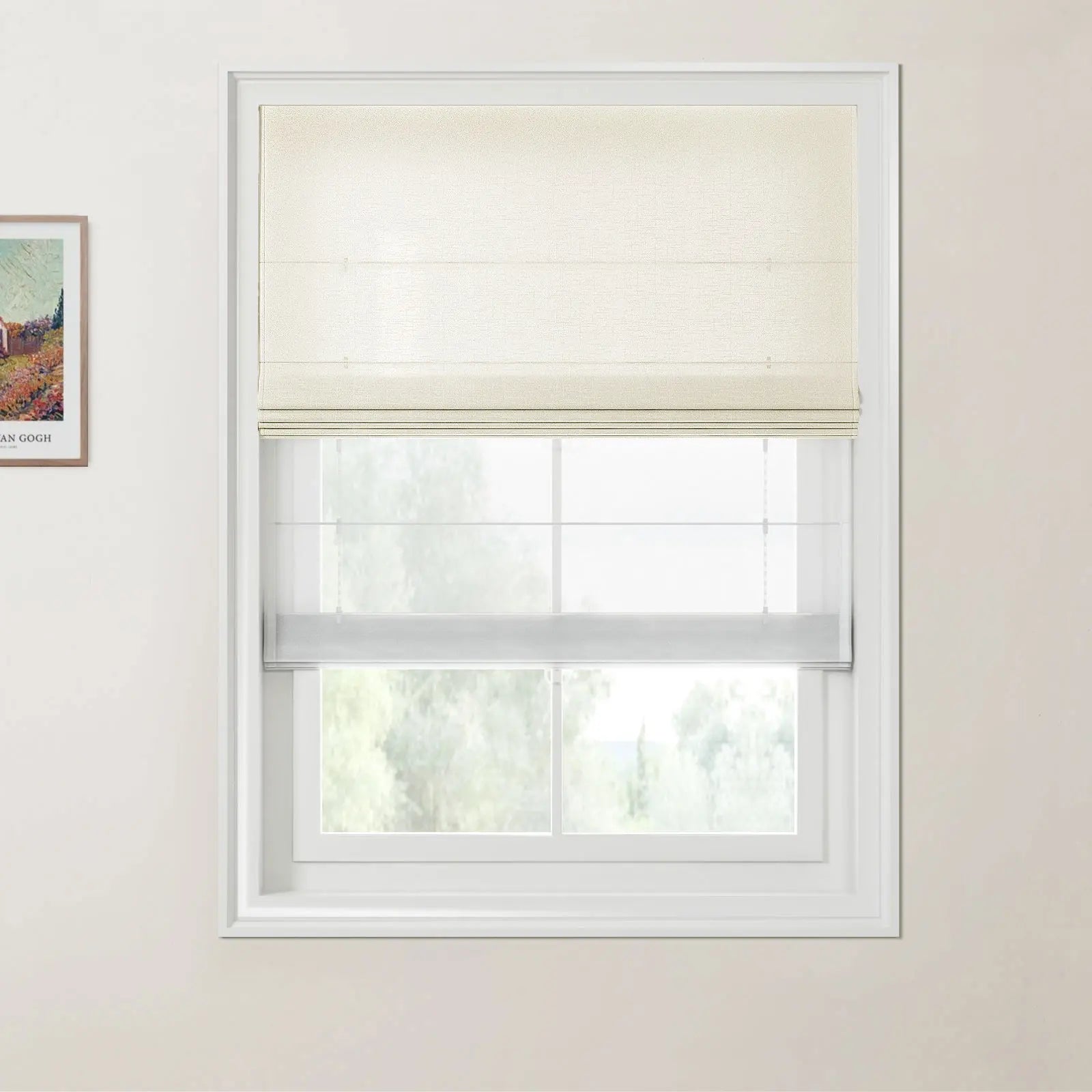 Framed Van Gogh landscape print on a cream wall next to a white window featuring a beige Roman blind and a sheer white blind with a blurred view of green trees outside