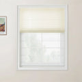 A photograph showing an interior window fitted with a partially lowered cream textured Roman blind, white grid windowpanes, light beige walls, and a visible framed Van Gogh print on the adjacent wall