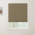 Photograph of a partially raised brown woven textured Roman blind in a white framed window against a light wall, featuring a blurred green outdoor view and a corner of a Van Gogh print