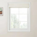 Van Gogh print a framed landscape painting on a light wall next to a white gridded window with a textured beige Roman blind overlooking blurry green trees