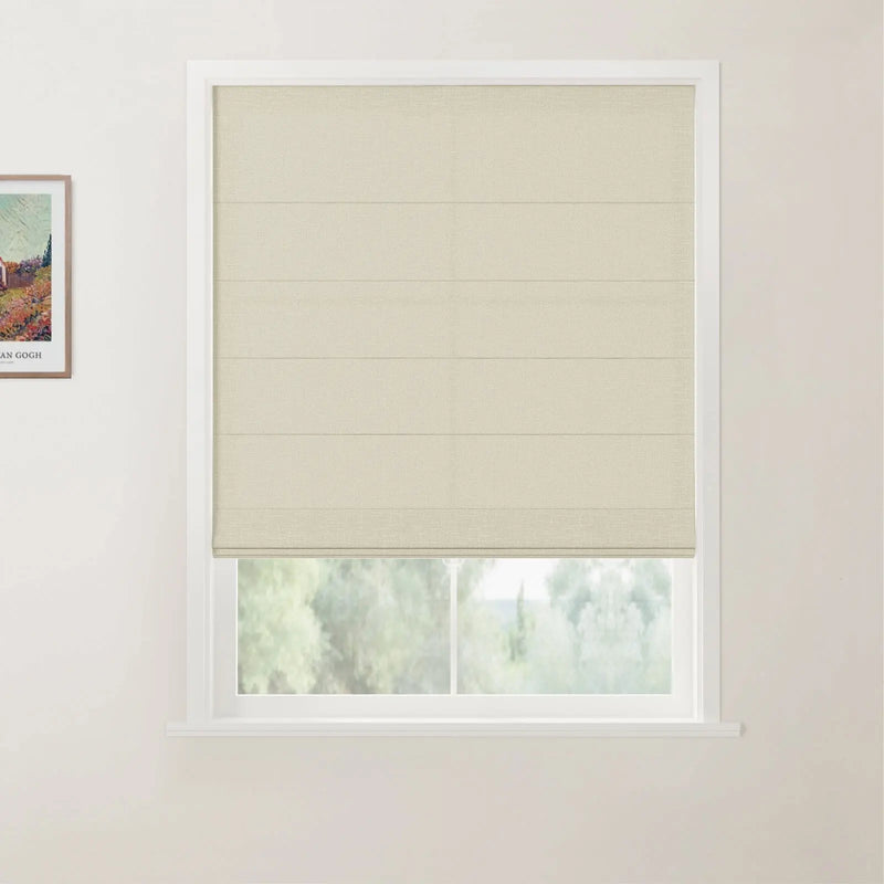 Photograph of a window with a cream textured roman blind and white frame, a framed Van Gogh print on the adjacent white wall, looking out to blurred green trees