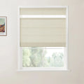 Photograph of cream-colored layered window shades installed on a white window frame, with a partial Van Gogh print visible on the light beige wall and a soft green landscape outside