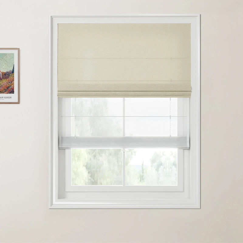 Photograph of a window with a textured beige Roman blind layered over a white sheer blind, revealing a blurred view of green trees, and a framed Van Gogh print on the adjacent left wall