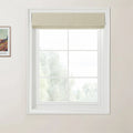 Photograph of a brightly lit interior featuring a white six-pane window with a light beige textured Roman blind and a partially visible Van Gogh print on the left wall, looking out to blurred green foliage