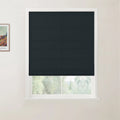 Photograph of a white-framed window featuring a dark charcoal textured Roman blind, partially revealing a vibrant green outdoor view, with a framed Van Gogh print on the adjacent wall