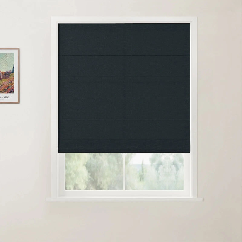 Photograph of a white-framed window featuring a dark charcoal textured Roman blind, partially revealing a vibrant green outdoor view, with a framed Van Gogh print on the adjacent wall