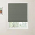 A modern interior features a textured grey-green Roman blind covering a white-framed window with blurred green foliage outside and a framed Van Gogh print on the adjacent wall
