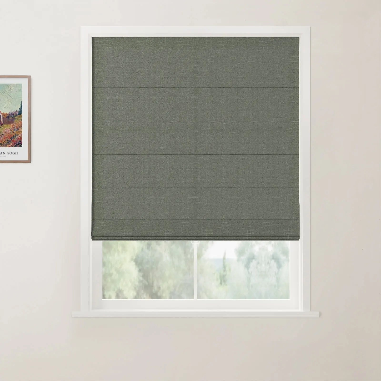 A modern interior features a textured grey-green Roman blind covering a white-framed window with blurred green foliage outside and a framed Van Gogh print on the adjacent wall
