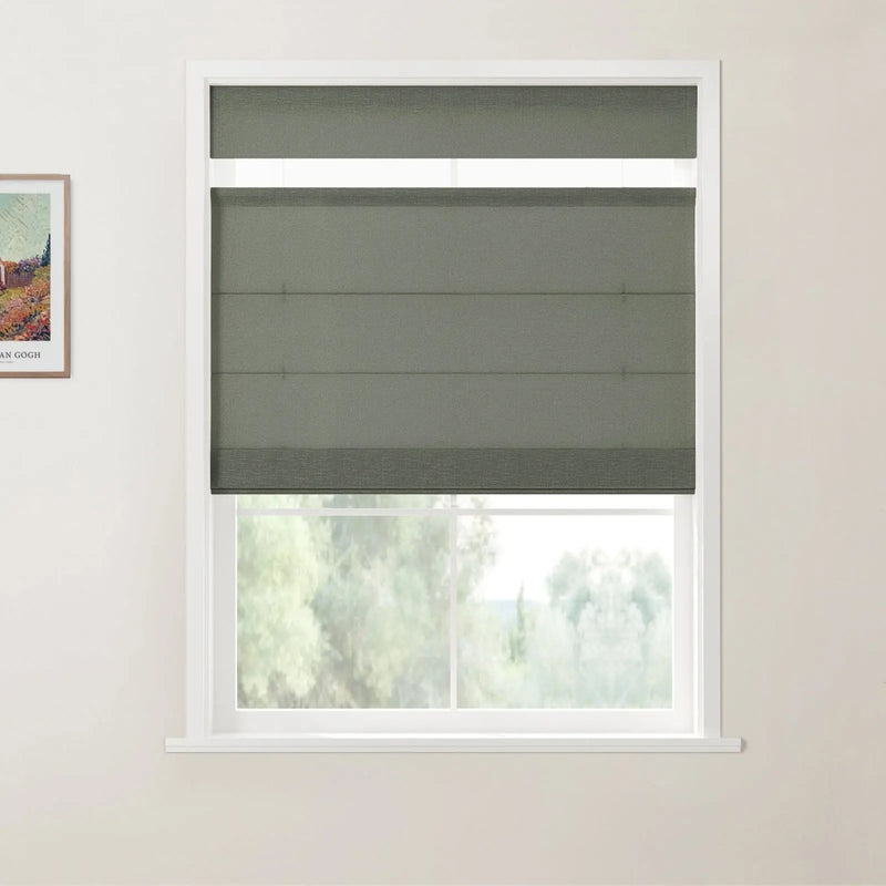 Print of a Van Gogh painting beside a white-framed window with a textured dark olive green Roman blind partially revealing blurry green trees in an interior room