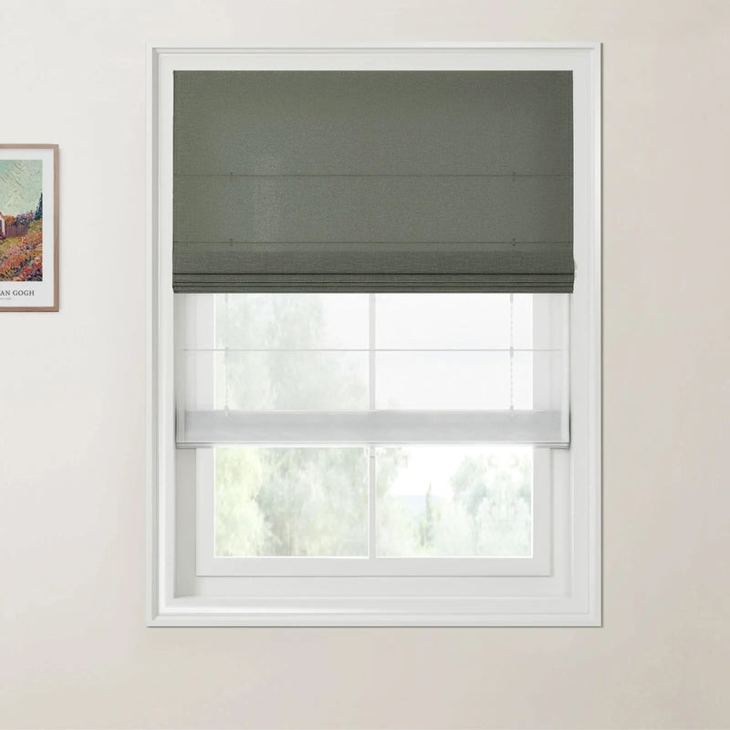 A white-framed window features a dark green roman blind over a sheer white bottom-up cellular blind, complemented by a framed Van Gogh print on the left wall and soft green trees outside