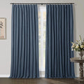 Dark blue pinch pleat curtains frame a multi-pane window in a room featuring a rustic wood side table with a silver vase of white flowers and a framed abstract plant artwork