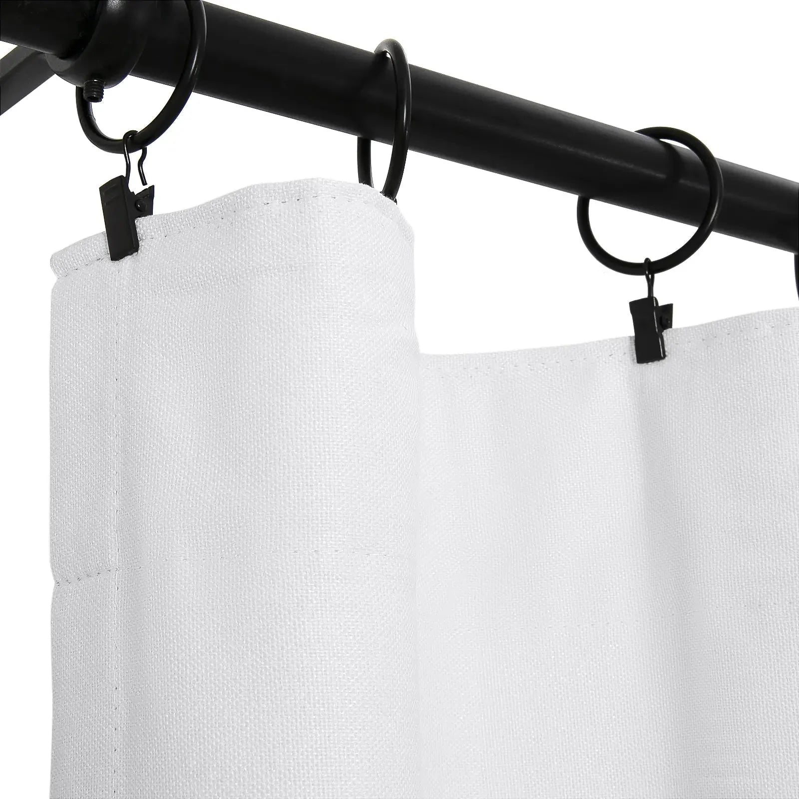 Close-up of a white textured fabric shower curtain suspended by matte black clip rings on a sleek black curtain rod