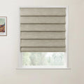 A framed Van Gogh print hangs beside a window fitted with a partially lowered natural beige faux linen Roman blind, revealing blurred green foliage outside