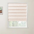 Photograph of a natural linen pleated Roman blind covering the upper part of a white window, revealing blurred green foliage outside, with a framed colorful Van Gogh landscape print on the adjacent light wall