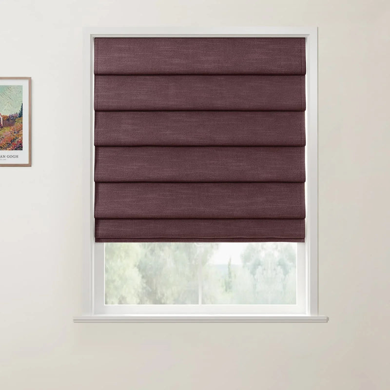 Print by Van Gogh on a white wall beside a white window frame with deep plum textured Roman blinds partially open to blurry green foliage