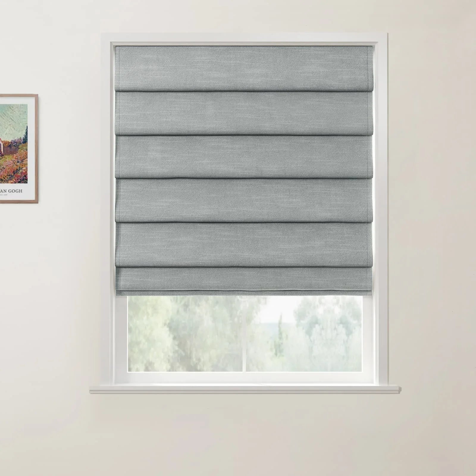 Photograph, featuring a framed Van Gogh print of a vibrant vineyard beside a window with white trim and folded grey Roman blinds, offering a glimpse of blurred green trees outside