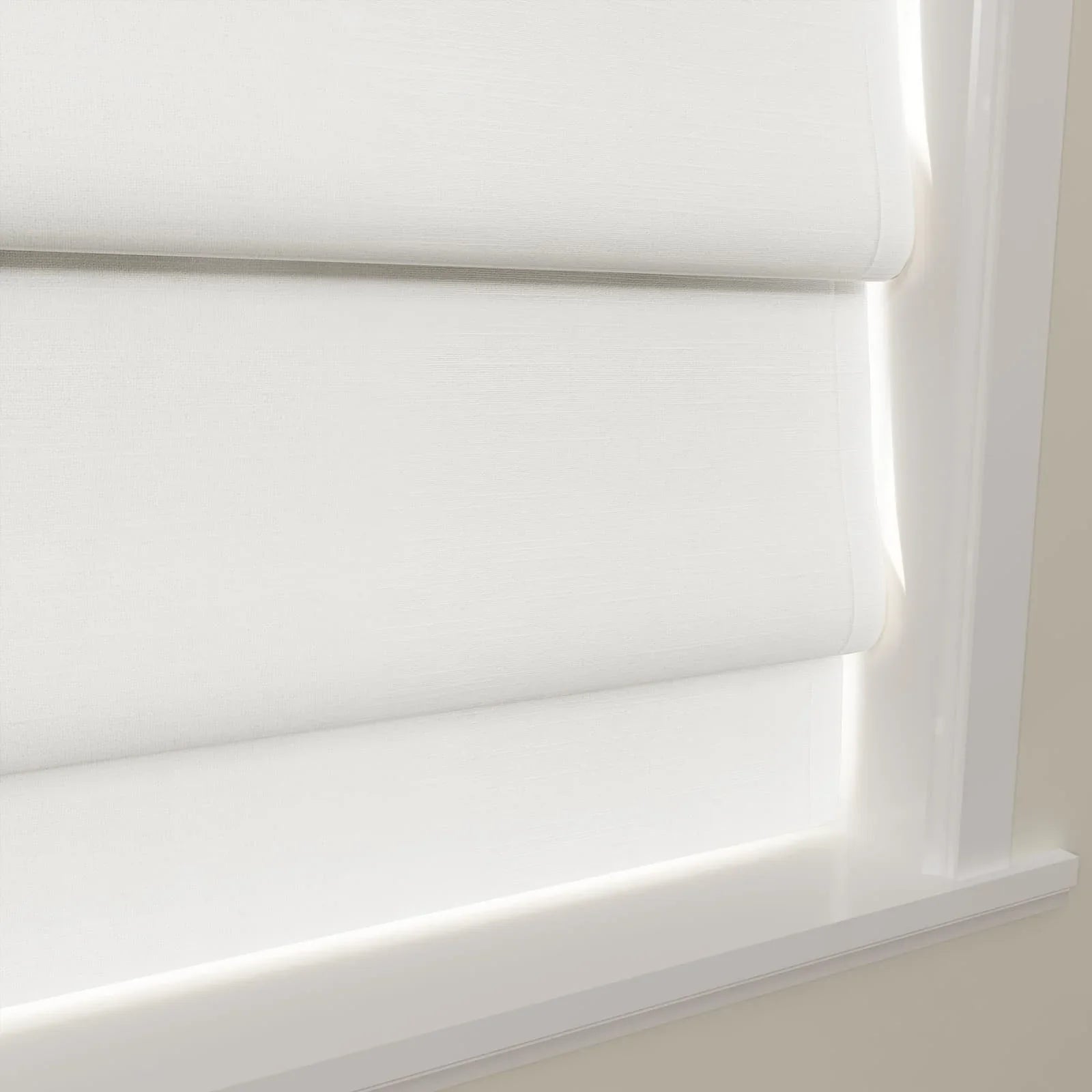 A pair of layered white textured window blinds showcasing a subtle weave and soft light filtering, set within a bright white window frame and sill against a neutral wall