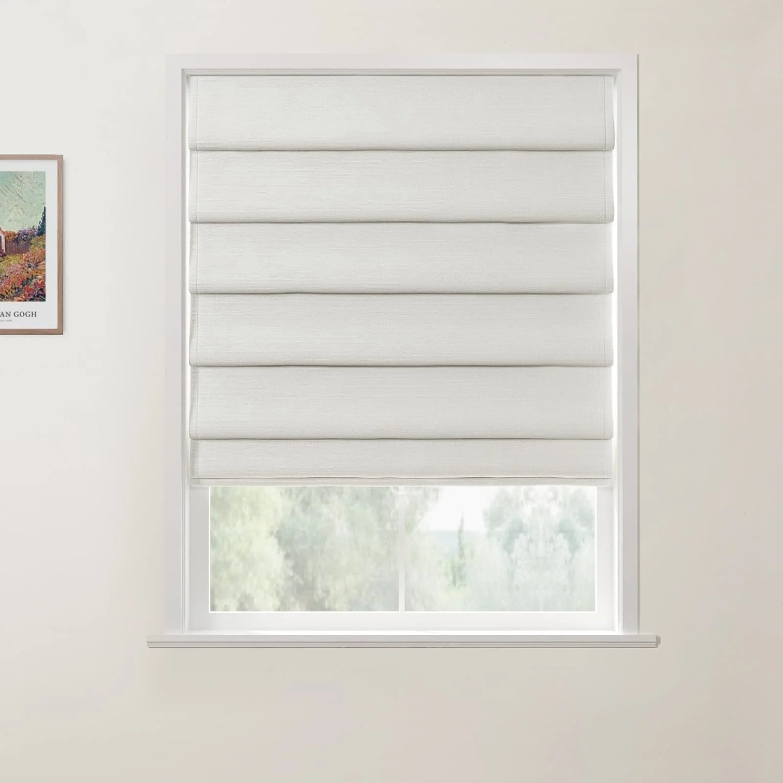 Photograph of a white textured Roman blind partially lowered in a window, with a view of green trees outside and a framed Van Gogh print on the left wall