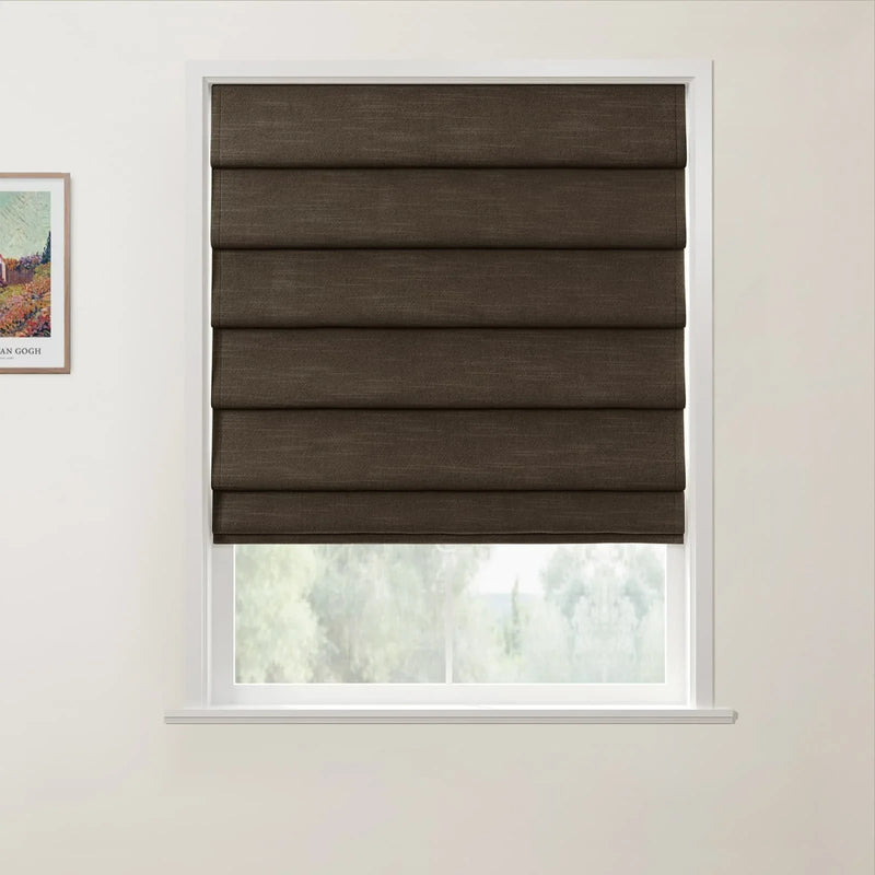 A dark brown textured Roman blind within a white window frame showcasing a blurred green outdoor landscape and a framed Van Gogh print on the adjacent white wall