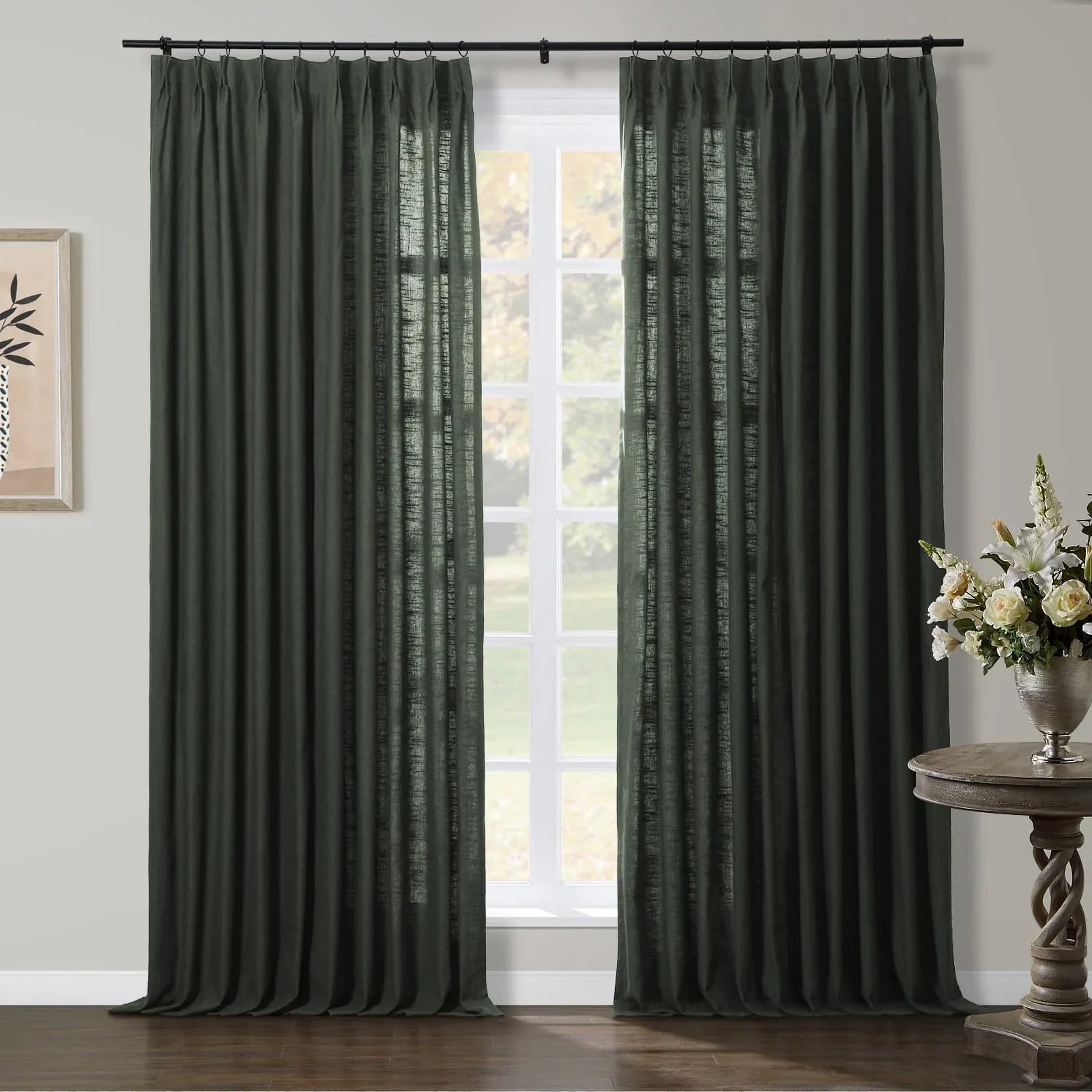 Dark olive green linen pinch-pleat curtains framing a large window in a contemporary interior featuring an elegant silver vase with white and cream flowers on a rustic carved wooden table and framed abstract botanical art