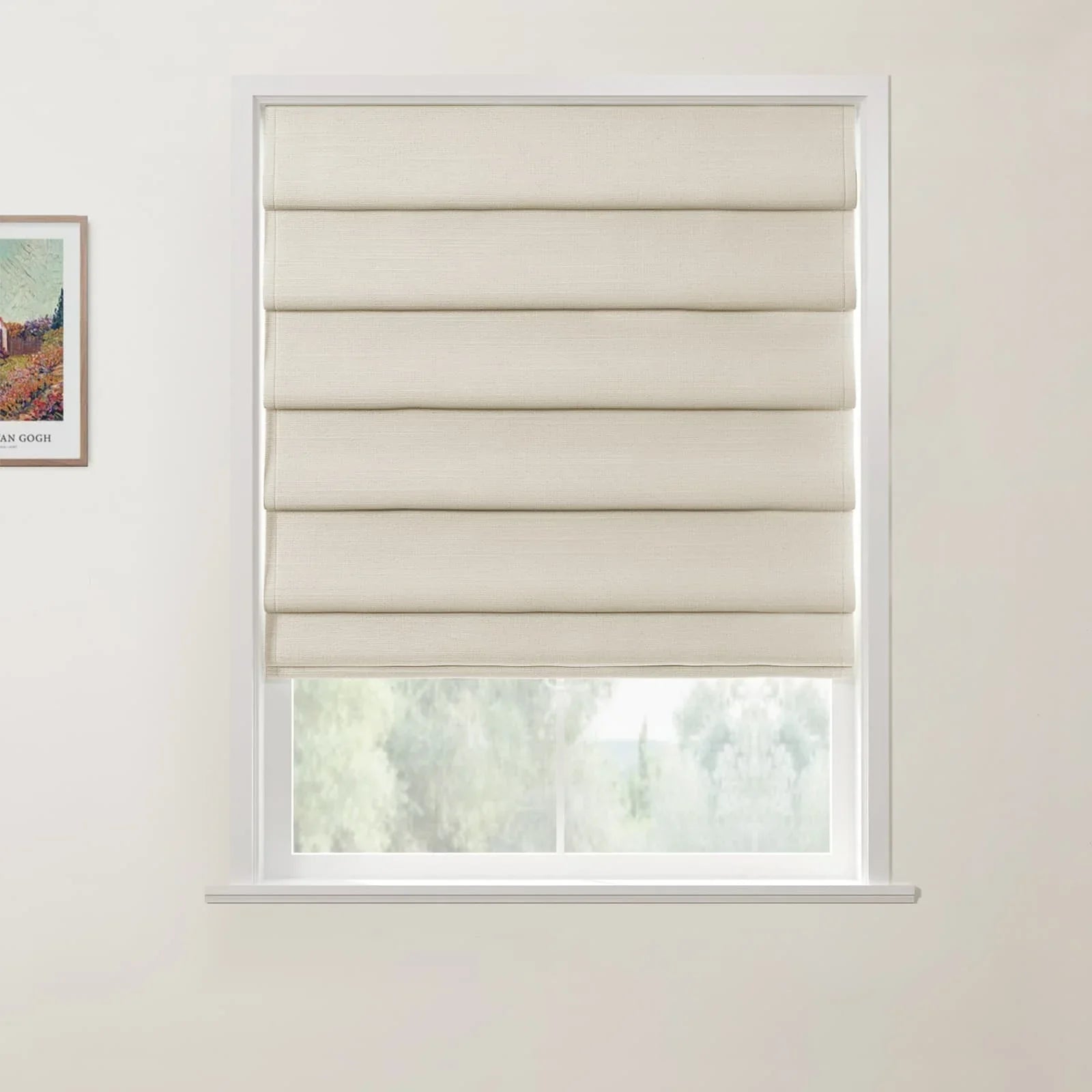 Photograph of a window featuring a cream textured fabric Roman blind with neat horizontal folds, partially revealing blurred green trees outside, with a framed Van Gogh art print on the adjacent white wall