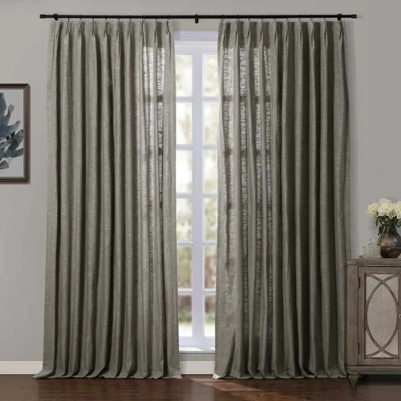 A pair of long olive green linen textured curtains with pleated tops in a contemporary interior room featuring a dark wood floor, decorative cabinet with fresh white flowers, and abstract artwork