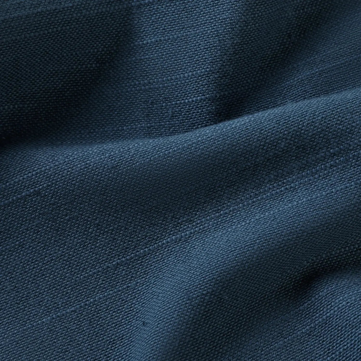 Textile deep indigo blue fabric showcasing a prominent woven texture with soft, undulating folds creating subtle shadows