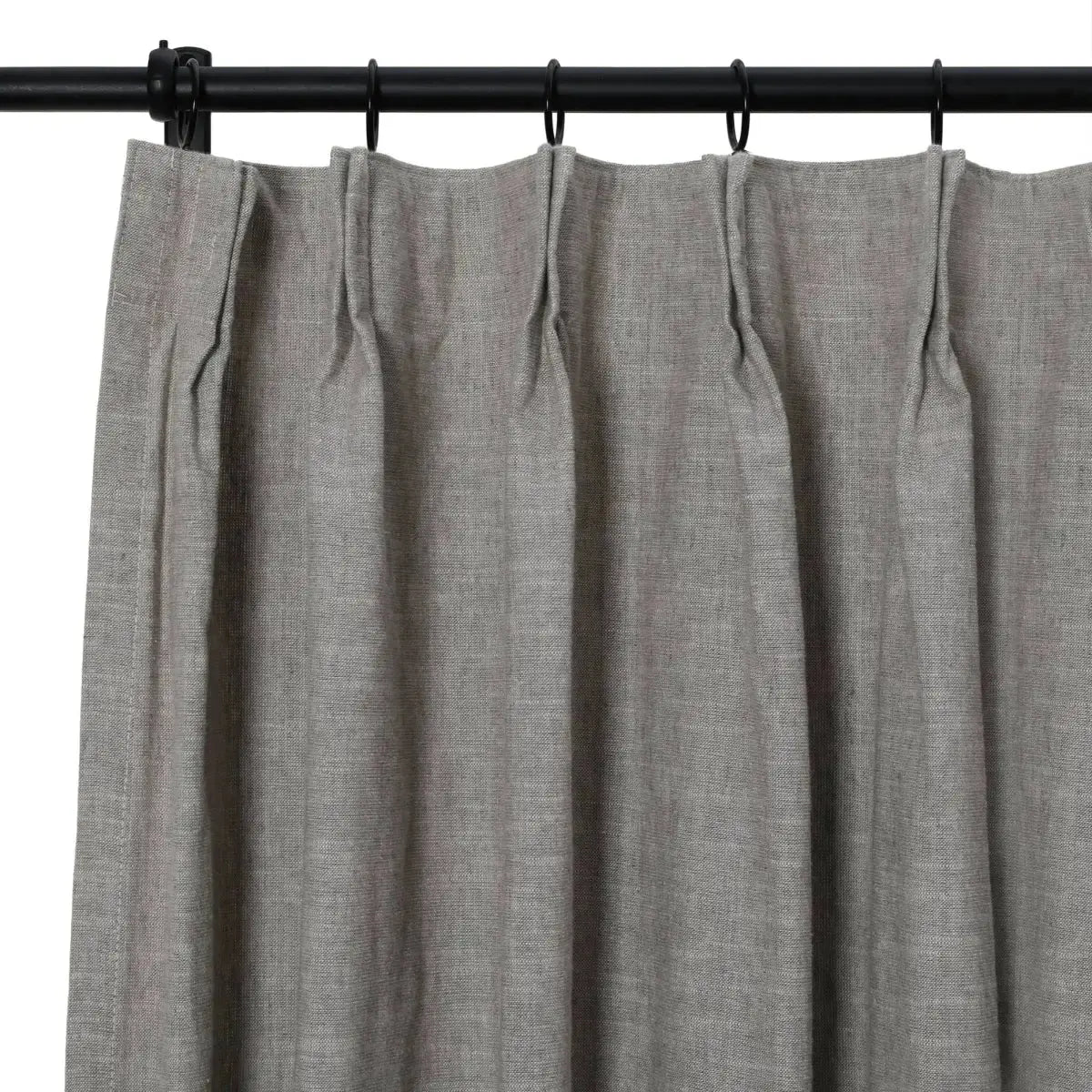 Photograph of a muted gray linen-blend pleated curtain on a black curtain rod with distinct woven texture and crisp pleats held by black rings