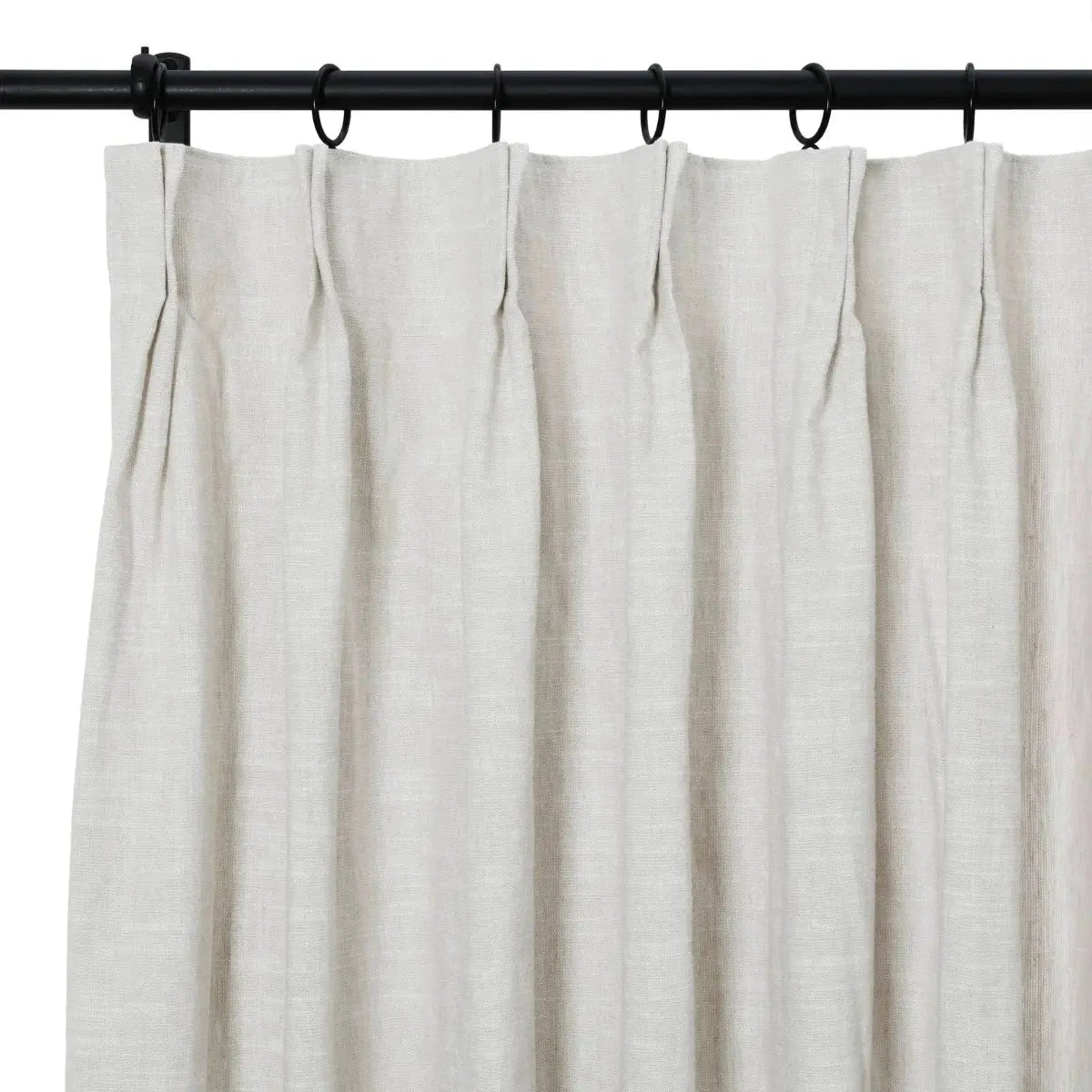 A light beige natural linen curtain with a pleated header hanging from black metal rings on a rod