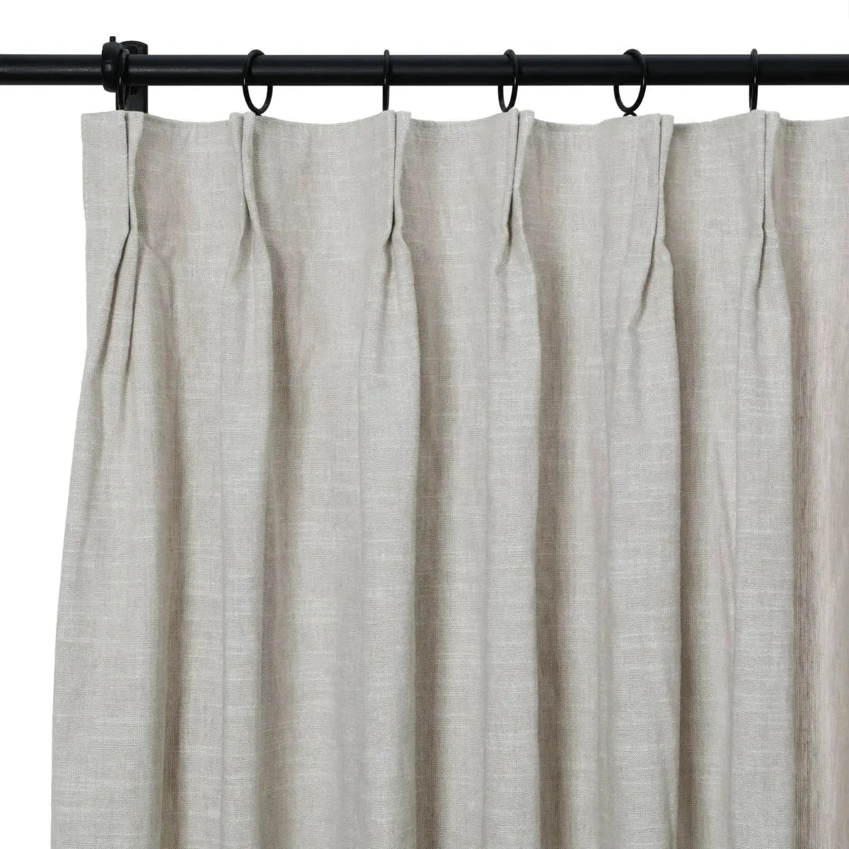 A light grey linen-look curtain with pinch pleats hung on a black rod and rings
