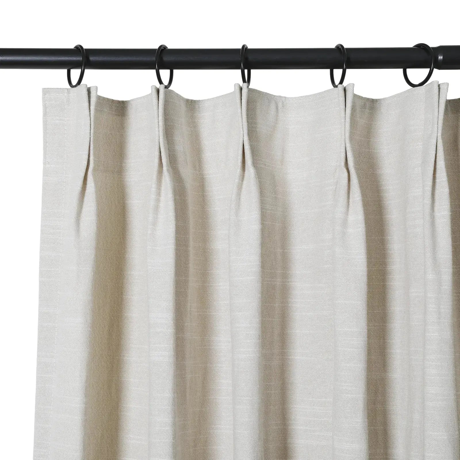 Light beige textured fabric pinch pleat curtain hanging from a black metal rod with visible black rings against a plain white background