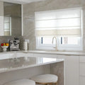 Photograph of a modern residential kitchen with light gray marble countertops, a sleek silver espresso machine, and a bowl of colorful fruit
