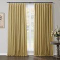 Textured gold curtains framing a window in a room, with a black curtain rod, a rustic carved wooden accent table, and a silver vase of white flowers