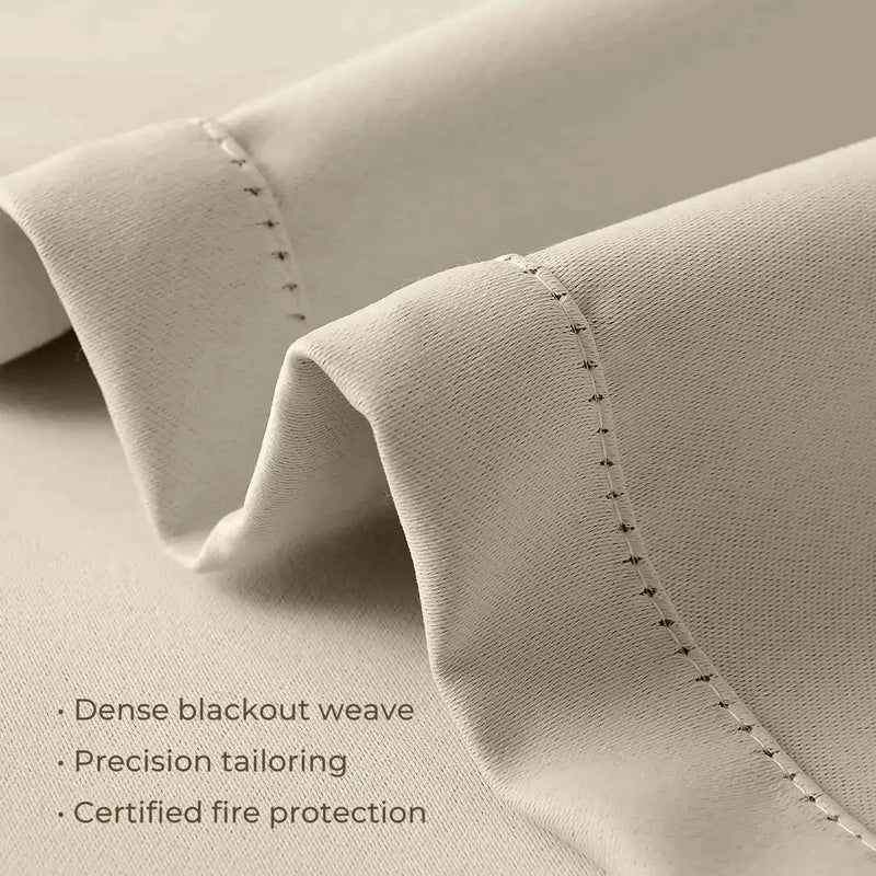 Photograph of light beige blackout curtain fabric showcasing a dense weave, precision tailoring with fine visible stitching, and certified fire protection features
