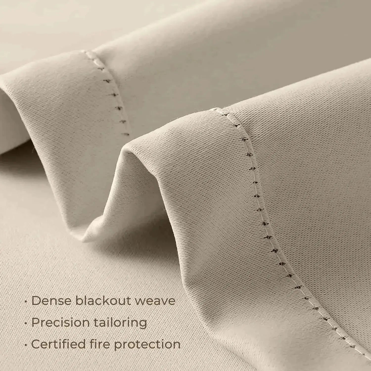 Photograph of light beige blackout curtain fabric showcasing a dense weave, precision tailoring with fine visible stitching, and certified fire protection features