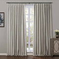 Window featuring light greige textured linen blackout curtains on a black rod, a rustic wooden cabinet with mirrored doors, and a framed abstract blue artwork