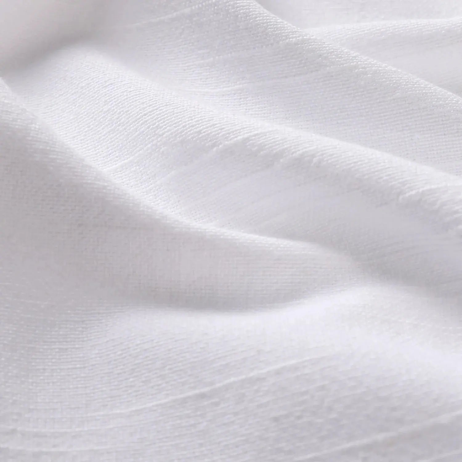 Close-up photograph of white textured fabric displaying gentle folds subtle shadows and a fine linen-like weave