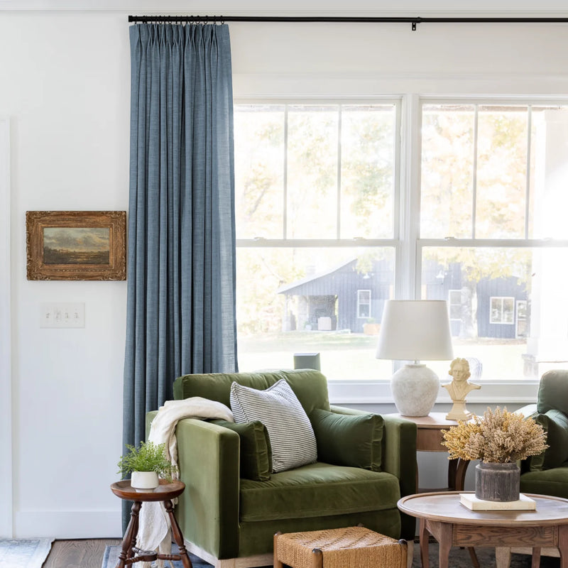 Aegean Blue Liz linen curtains shown closer beside a sunlit window with smooth vertical folds